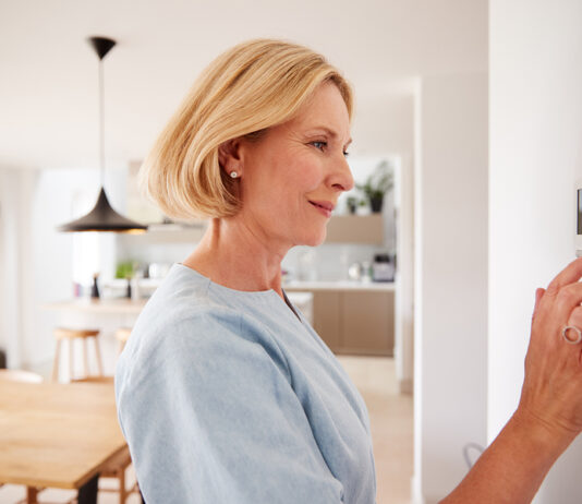 Vorlauftemperatur richtig einstellen und optimal heizen Frau stellt Thermostat ein