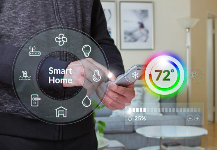 Mann hält ein iphone vor einem Haus während sie die Heizung mit Smart Home App steuert
